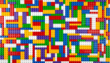 Renkli yapı bloklarının soyut arkaplan dokusu. İnşaatçının renkli plastik parçalarının arka planı. Renkli oyuncak yığınları..