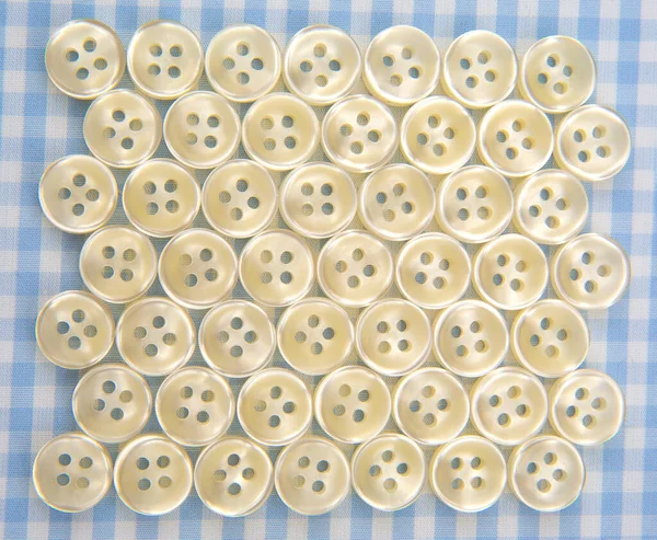 Plastic shiny buttons for clothes on a fabric background. Fashion and clothing. Factory industry