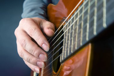man plays the classical guitar. string musical instrument. hands of the musician playing on classical guitar