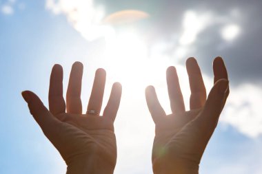 raised woman hand against the sunny sky