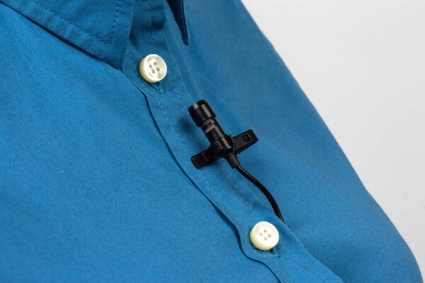 clip-on lavalier microphone is attached to women clothing close-up. Audio recording of the sound of the voice on a condenser microphone.