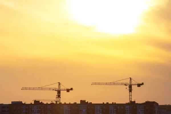 silhouettes of building cranes in the evening sky against the backdrop of sunset. urban building industry