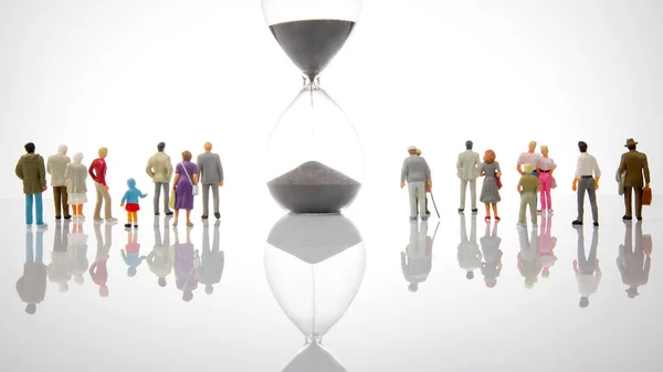 miniature people. people of different ages and statuses stand in line near the hourglass. the concept of the importance of time and life