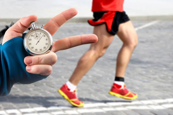 Premium Photo  Measuring the running speed of an athlete using a  mechanical stopwatch. hand with a stopwatch on the background of the legs  of a runner.
