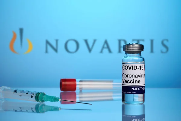 Vacuna y jeringa Novartis Covid sobre fondo azul degradado — Foto de Stock