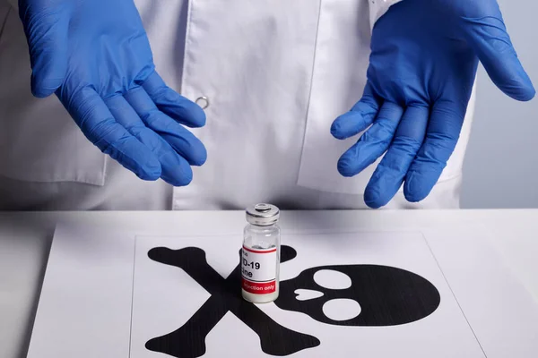Доктор показывает вакцину Ковида и печатный символ смерти — стоковое фото