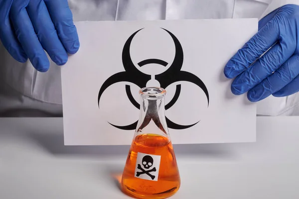 Médico muestra símbolo de peligro biológico en la página y la toxina naranja - Labs Photo —  Fotos de Stock