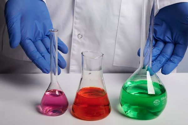 Doctor Scientist Shows Colored Chemical Flasks - Labs Photo — Stock Photo, Image