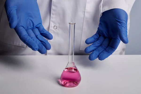Lékař ukazuje chemické baňky s růžovou vodou - Laboratoře Photo — Stock fotografie