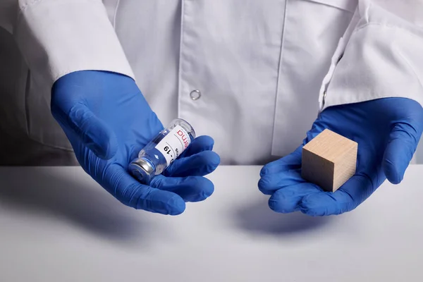 医者は現代コヴィドワクチンと木製のキューブを提供しています-医学研究室写真 — ストック写真