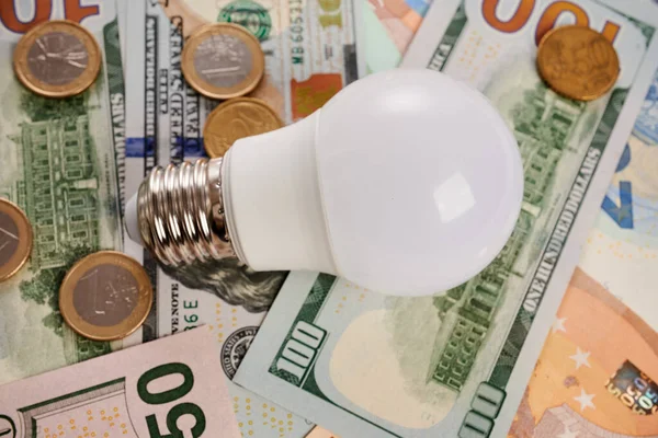 Żarówka LED i monety - zdjęcie na temat rachunków pieniężnych — Zdjęcie stockowe