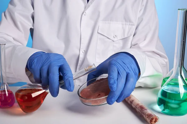 Foto do médico com frasco químico e carne transgênica em prato de Petri — Fotografia de Stock