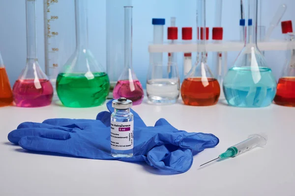 Вакцина и перчатка Astrazeneca Covid на химическом столе - Медицинская лаборатория Фото — стоковое фото