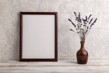 Kahverengi ahşap çerçeve modeli ve gri beton arka planda seramik vazoda lavanta. Boş, dikey yönelim, natürmort yaşam, kopyalama alanı.