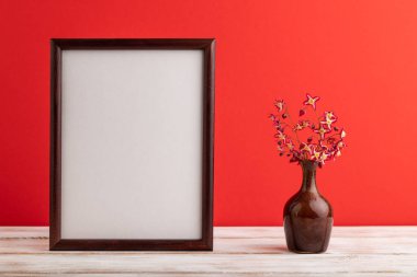 Kırmızı pastel arka planda seramik vazoda mor barrenwort çiçekleri olan ahşap çerçeve. Yan görünüm, kopyalama alanı, natürmort, model, şablon, bahar, yaz minimalizmi kavramı.