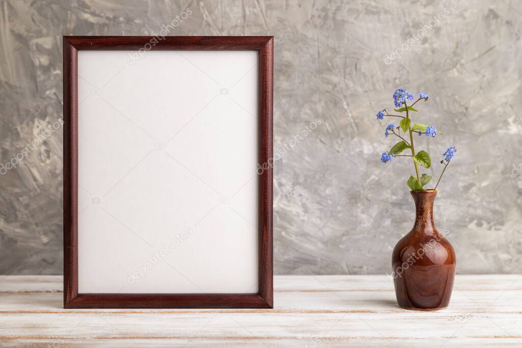 Wooden frame with blue forget-me-not flowers in ceramic vase on gray concrete background. side view, copy space, still life, mockup, template, spring, summer minimalism concept.