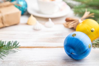 Noel veya Yeni Yıl kompozisyonu. Süslemeler, kutular, toplar, tarçın, kurdeleler, köknar ve ladin dalları, bir fincan kahve, beyaz ahşap arka planda. Yan görünüm, kopyalama alanı, seçici odak.