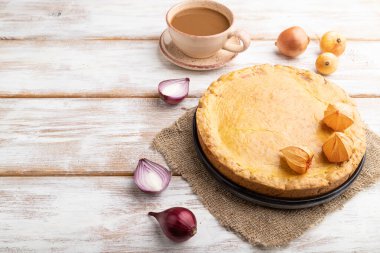 Sonbahar soğanlı turta ve beyaz ahşap arka planda bir fincan kahve ve keten tekstil. Yan görünüm, boşluk kopyala.