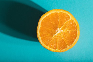 Olgun, mavi pastel arka planda turuncu kesilmiş. Üst manzara, düz yatış, yakın çekim, sert ışık. Tropik, sağlıklı gıda, konsept, minimalizm.