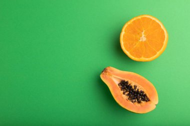 Olgun kesim turuncu ve yeşil pastel arka planda papaya. Üst görünüm, düz görünüm, kopyalama alanı. Tropik, sağlıklı gıda, konsept, minimalizm.