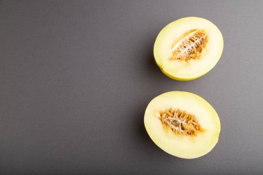 Gri pastel arka planda dilimlenmiş olgun sarı kavun. Üst görünüm, düz görünüm, kopyalama alanı. hasat, kadın sağlığı, vegan gıda, konsept, minimalizm.