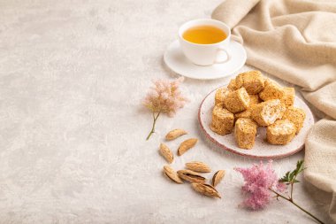 Geleneksel Türk lokumu (Raf lokum) gri beton arka plan ve keten tekstil üzerinde bir fincan yeşil çay ile. Yan görünüm, boşluk kopyala.