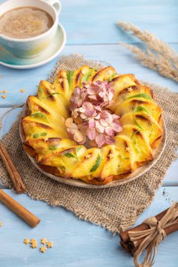 Mavi ahşap arka planda bir fincan kahveli cheesecake ve keten tekstil. Yan görünüm, kapat.