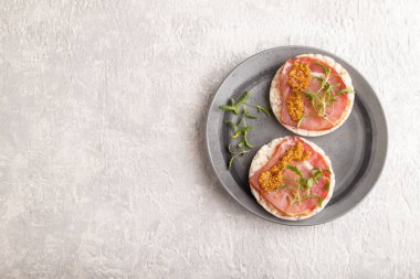 Kurutulmuş et, mikroyeşil ve hardallı pirinç keki sandviçleri gri beton arka planda. Üst görünüm, düz görünüm, kopyalama alanı.