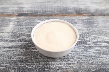 Seramik sos kasesinde gri ahşap arka planda mayonez var. Yan görünüm, kapat, boşluğu kopyala.