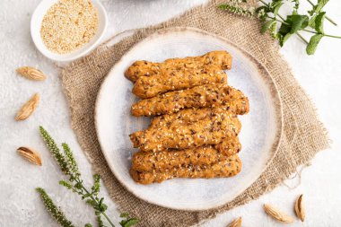 Baharatlı çörekler ve seramik tabakta badem, yeşil çay fincanı ve gri beton arka planda keten tekstil. Üst görünüm, düz görünüm, yakın çekim.