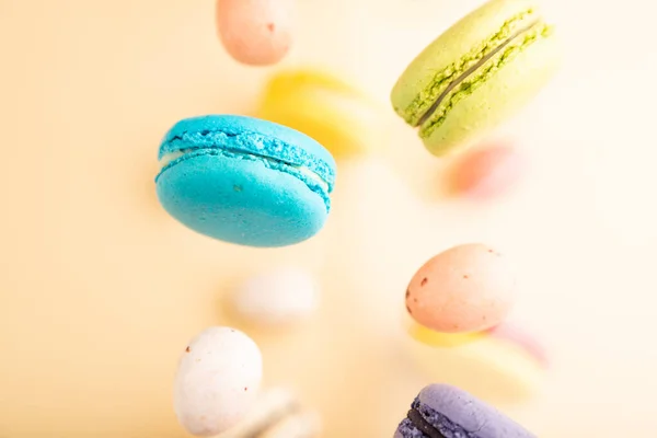 Multicolored Flying Macaroons Chocolate Eggs Frozen Air Blurred Beige Background — Stock Photo, Image