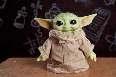 Ekim 2021: Bebek Yoda, Yıldız Savaşları 'nın aksiyon figürlerinden biri masada duruyor. Siyah arkaplan
