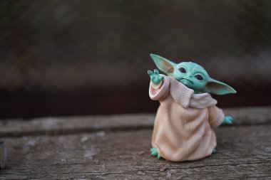 Ekim 2021: Bebek Yoda, eski ahşap masada duran Star Wars 'un aksiyon figürlerinden biri. Bokeh etkisi Arkaplanı