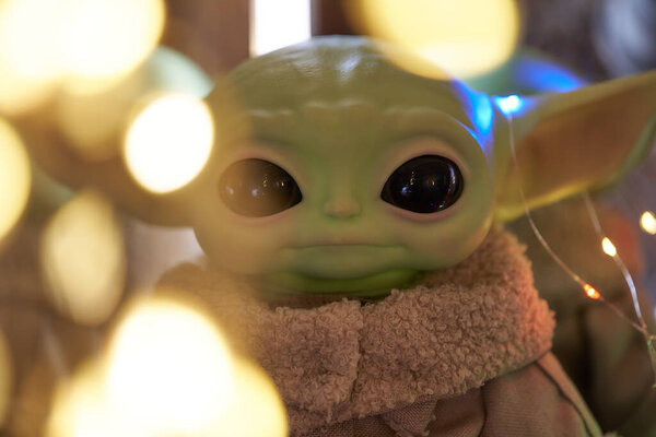 Октябрь, 2021: Малыш Йода, фигурки из Звёздных войн, стоящие на столе. Черный фон с огнями из разноцветной гирлянды