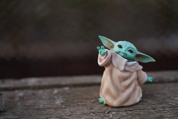 Octubre, 2021: Baby Yoda, una figura de acción de Star Wars de pie sobre la vieja mesa de madera. Efecto Bokeh Fondo —  Fotos de Stock