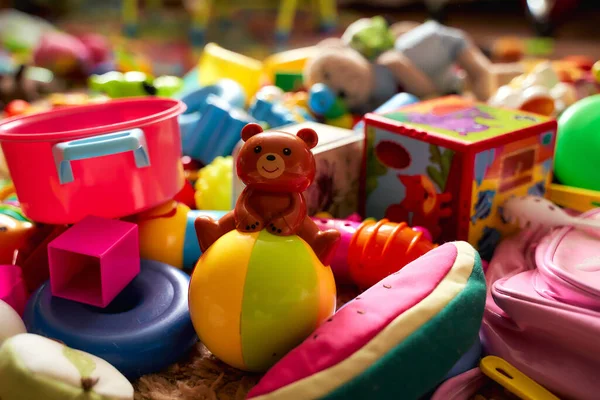 Brinquedos infantis. Uma vista de um tipo em forma de urso. O resto dos brinquedos estão espalhados no chão — Fotografia de Stock