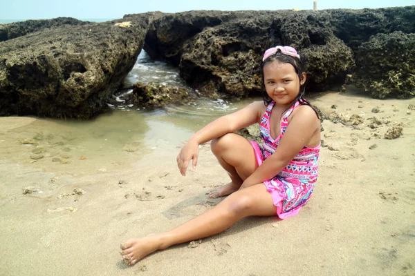 白い砂浜と岩の背景に水着とゴーグルを着た若いアジアの女の子 — ストック写真