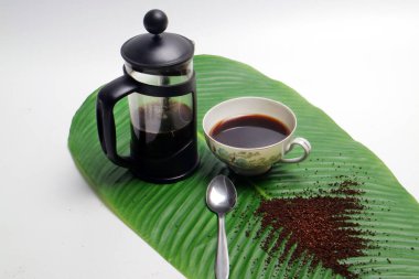 photo studio of french press coffee with cup of coffee spoon and coarse coffee powder on banana leaf white background clipart