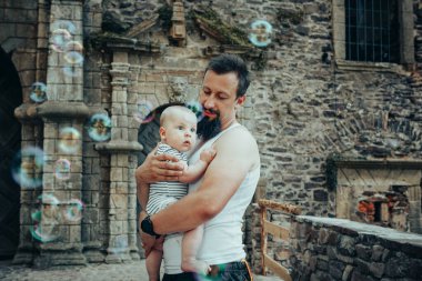 Baba kollarında bir bebekle sabun köpüğü ve eski bir şatoda