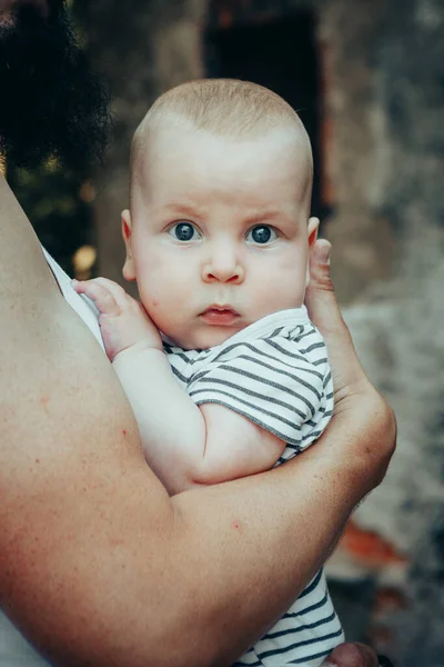 A six-month-old baby in the arms of a father against the backdrop of an old castle