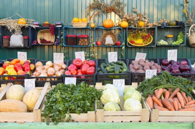 Markette sebzeler ve meyveler var. Kutularda: biber, soğan, domates, salatalık, patates, soğan, kavun, maydanoz, lahana, havuç.