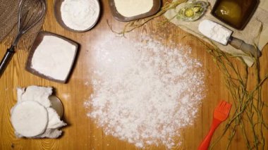 Ev yapımı çavdar ekmeği. Düz yatıyordu. Eldivenli erkek eller masaya çavdar ekmeği koyuyor. Masanın üzerinde ekmek unu (çavdar, buğday, mısır) mayalı, tuz, bal, yağ yapımında kullanılan malzemeler var..