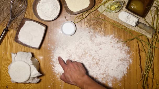 烤好的面包一个人的手用手指在面粉上写着 并把一块面包放在桌子旁边 桌上有制作面包的配料 — 图库视频影像