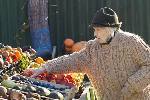 Grandma at the farmer\'s market. Grandmother held out her hand to take an apple from the box.