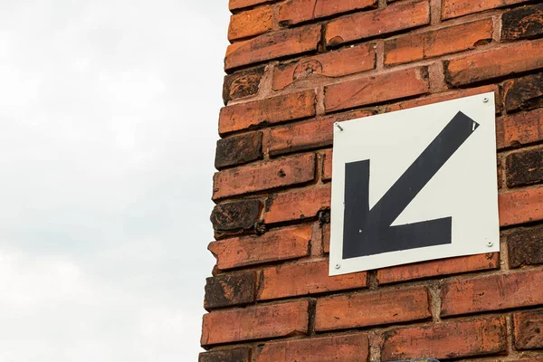 Beyaz arka planda siyah ok aşağı ve solu gösteriyor. Kırmızı tuğla duvar ve mavi gökyüzünün arka planına karşı. Boşluğu kopyala.