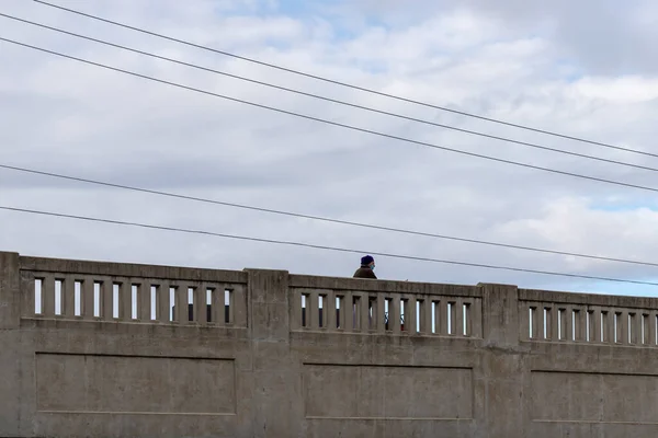 Cambridge, Ontario, Kanada - 23 Ekim 2021: Mavi sarıklı ve cerrahi maskeli yaşlı adam taş köprüden geçiyor. Su hatları tepemizde.. 