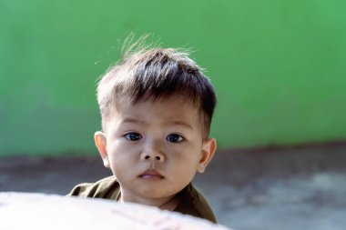 Kameraya bakan küçük bir çocuğun portresi. Anneye bakan bebeğin parlak gözlerine seçici bir şekilde odaklan. Covid tecridi sırasında evde dinlenen sevimli küçük çocuk. Pozitif çocuk konsepti