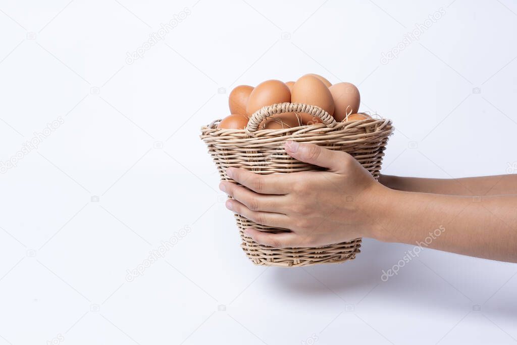 Woman hand holding fresh eggs collected inside wicker basket, suitable as a food ingredient or giving present. Fresh eggs from quality organic farms isolated on white background. Healthy food concept