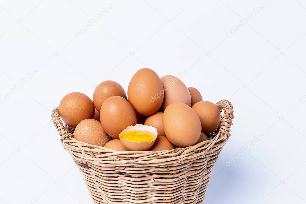 Fresh eggs collected inside wicker basket and one broken, suitable as a food ingredient. Fresh eggs from quality organic farms isolated on white background. Healthy food concept