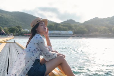 Happy woman wearing straw hat relaxing and watching views of sea and sky on tropical beach travel summer holidays. Beautiful young model tourist enjoy traveling to exotic nature in leisure time.  